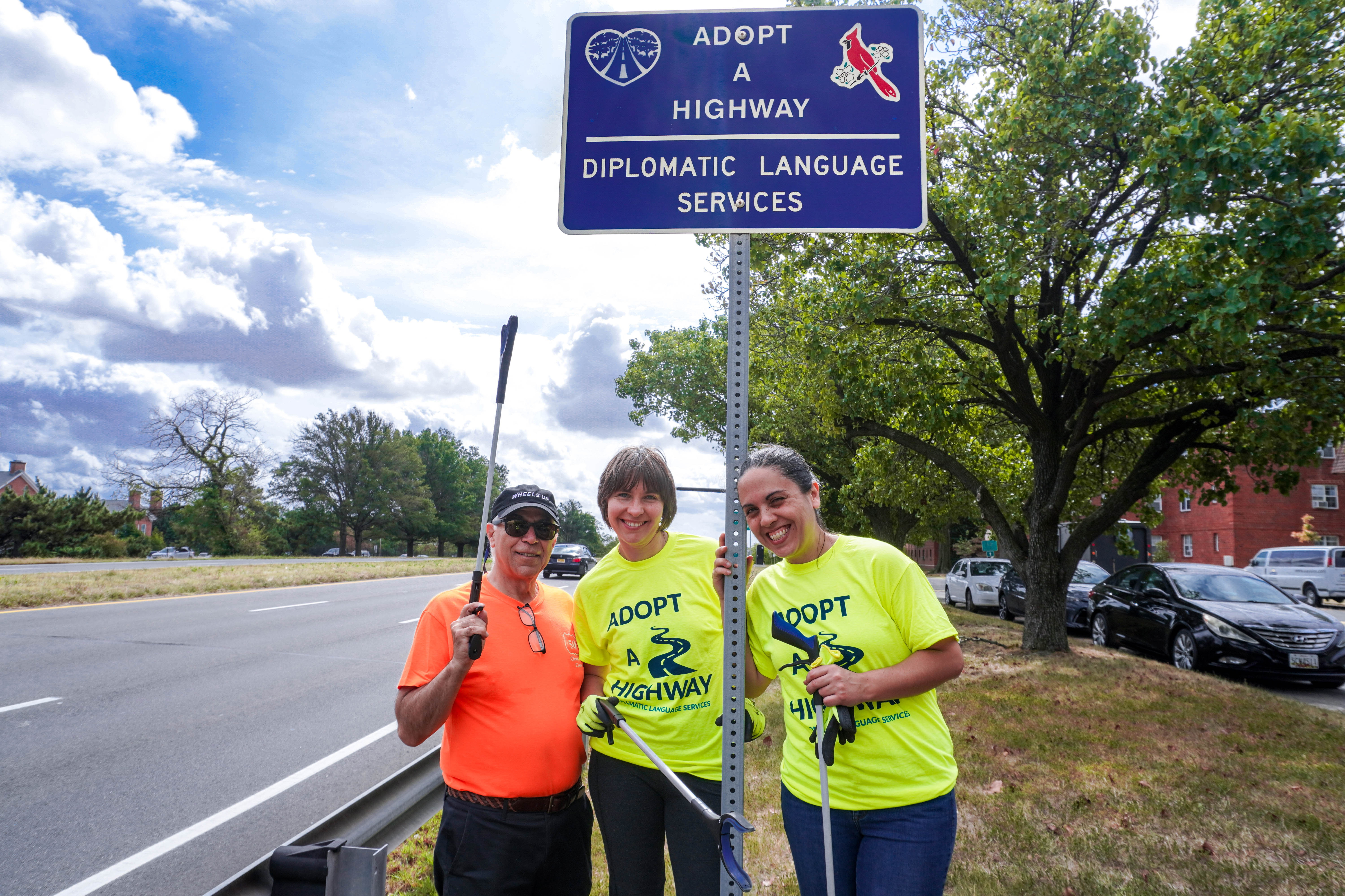 Diplomatic Language Services staff members stand with their adopt-a-highway sign along Route 50 in the Washington DC metro area